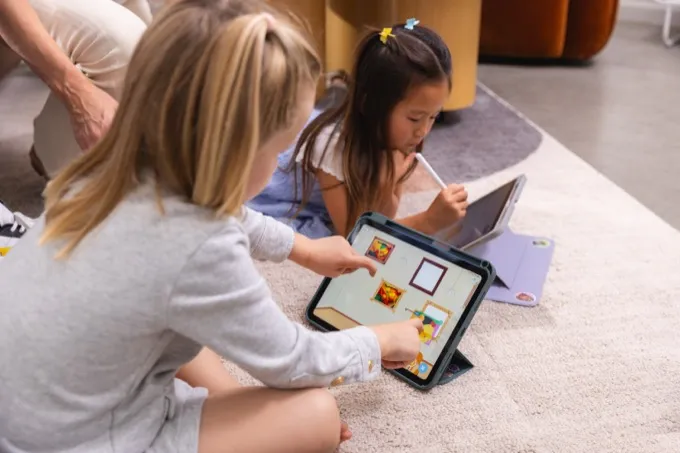 Kids drawing together on a tablet on the floor